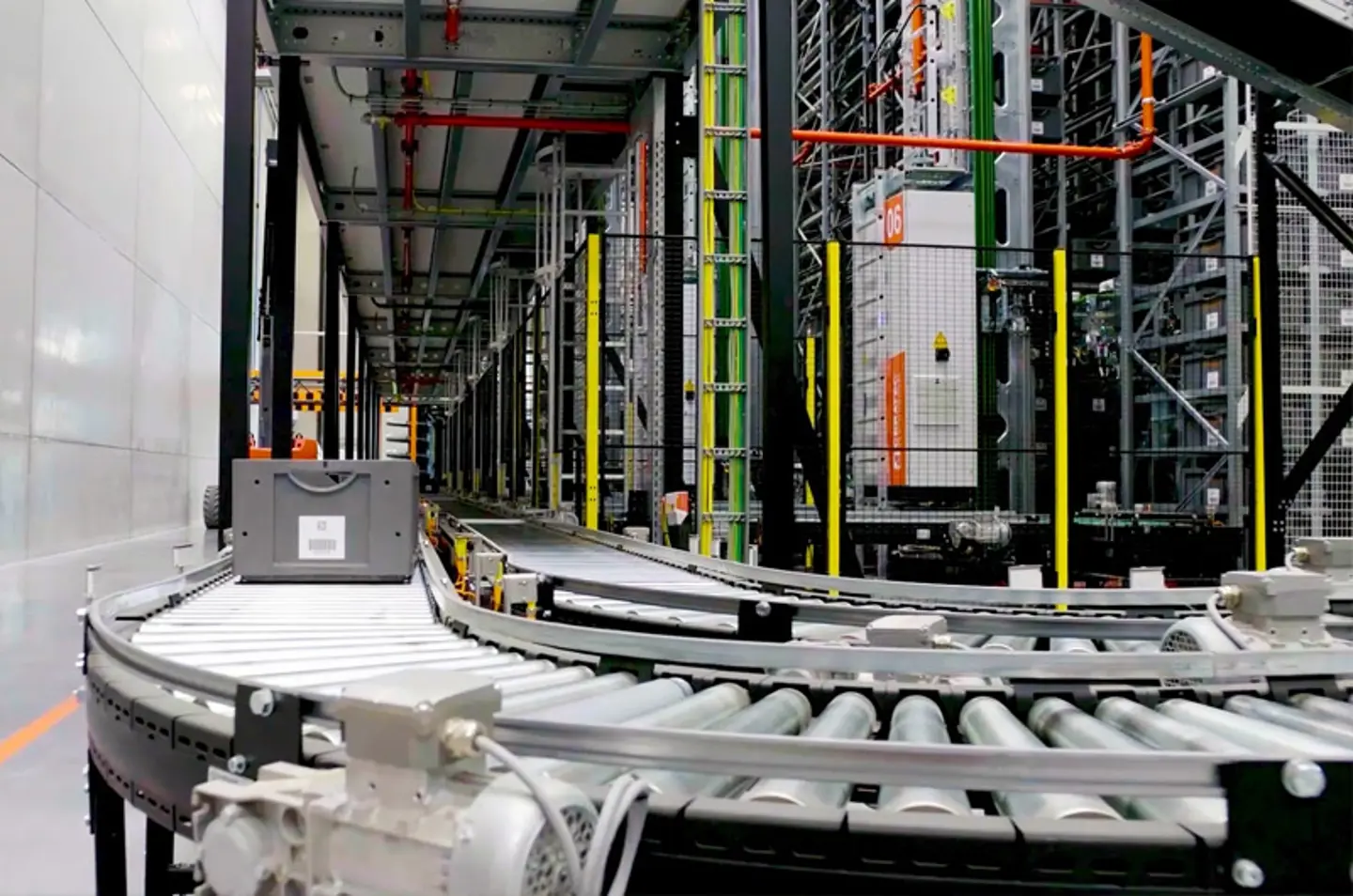 Système de convoyeurs automatisé dans un entrepôt avec pistes à rouleaux et clôtures de sécurité pour la manutention des marchandises.