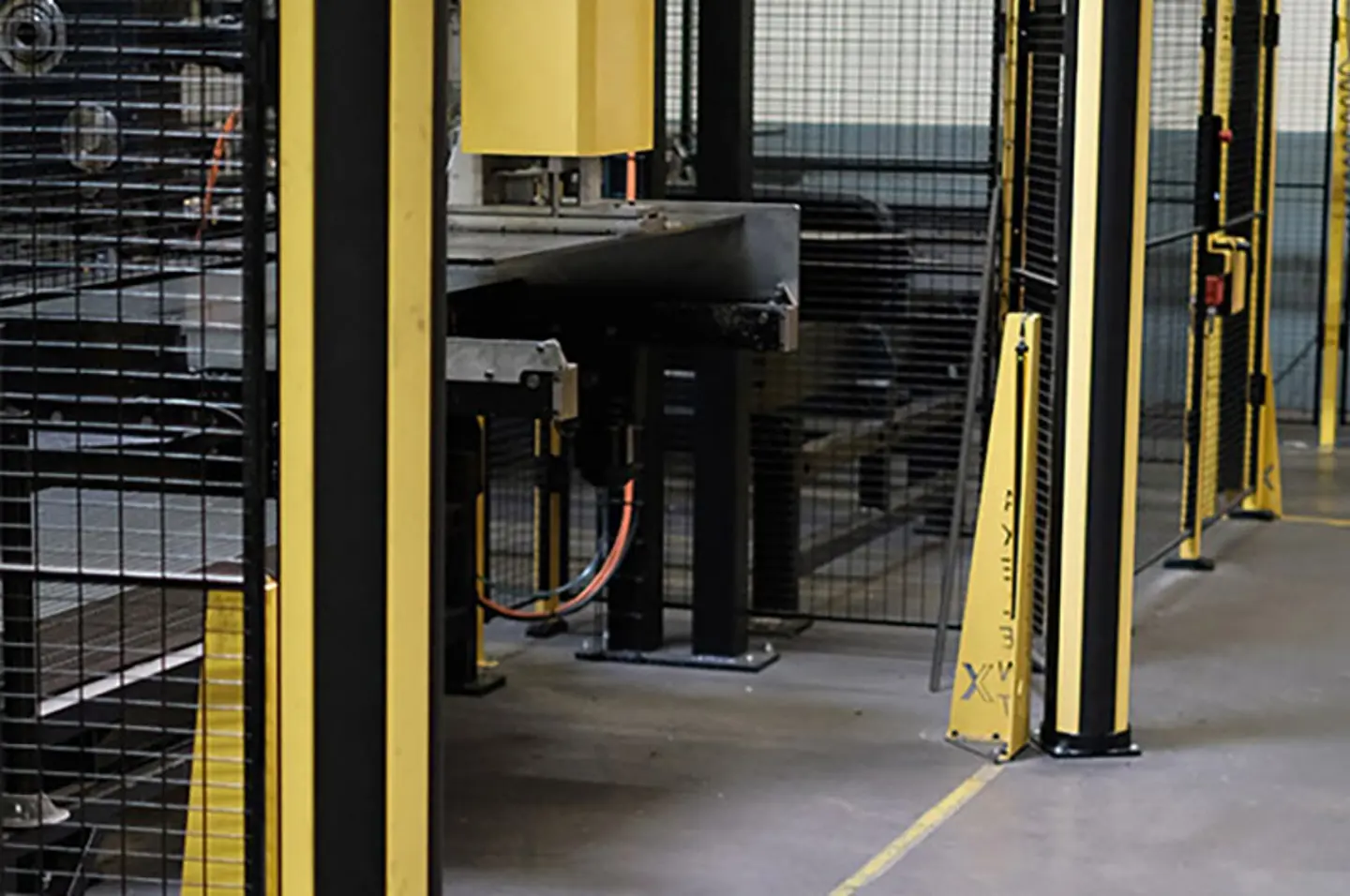 Barrières de sécurité en entrepôt et protecteurs de machines protégeant les allées piétonnes autour des systèmes automatisés de convoyeurs et de robots.