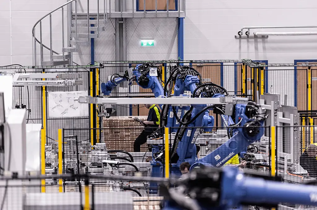 Bras robotiques palettisant des cartons à l’intérieur d’une cellule d’automatisation sécurisée.