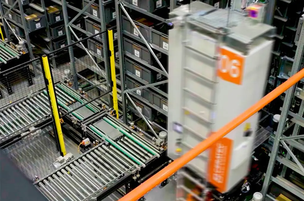 Entrepôt automatisé avec des convoyeurs et un robot de stockage rapide circulant entre de hauts rayonnages de bacs, illustrant l’automatisation logistique et la gestion intelligente des stocks.