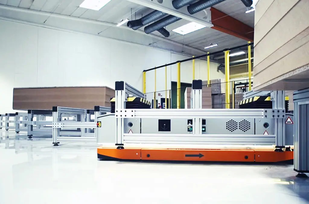 Robot mobile autonome (AMR) transportant des marchandises dans un entrepôt industriel.