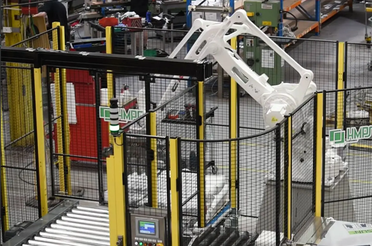 Palettiseur robotisé haute vitesse empilant des caisses sur des palettes dans une zone protégée.