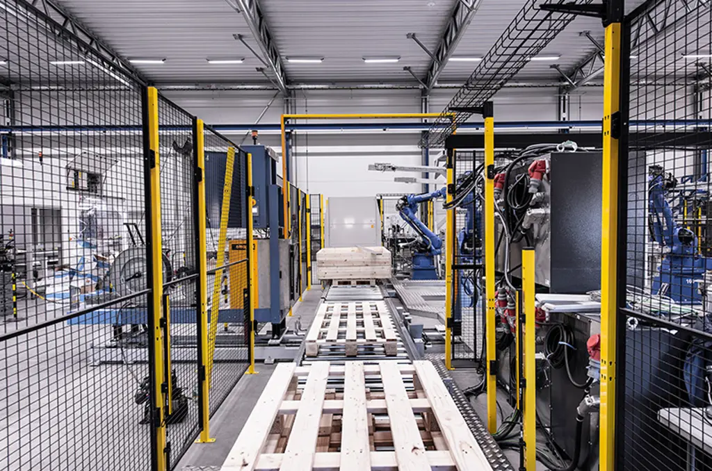 Ligne de palettisation automatisée avec bras robotiques et palettes dans une zone de sécurité.