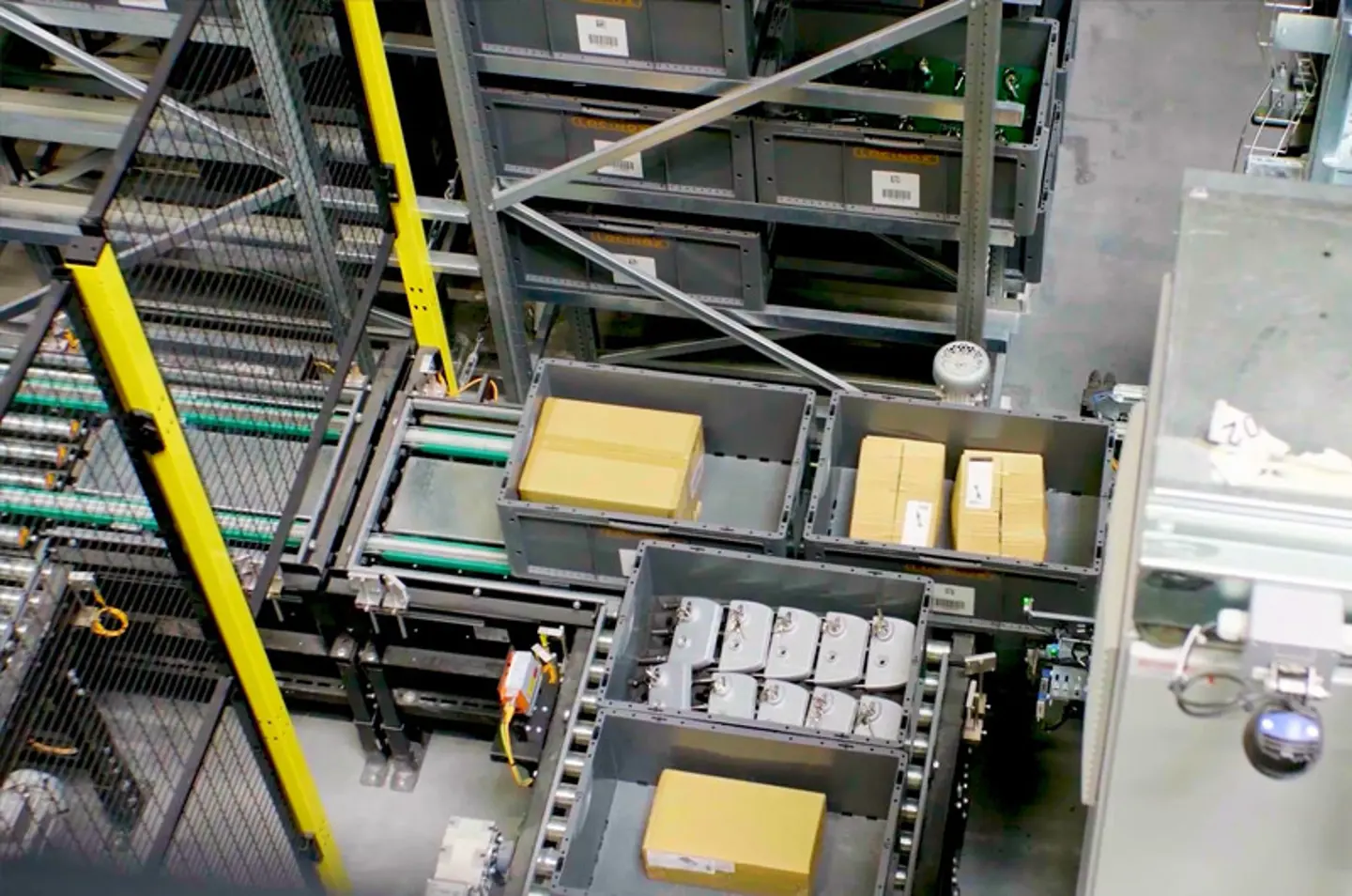 Système automatisé de manutention avec convoyeurs à rouleaux et bacs transportant des marchandises emballées, illustrant l’automatisation logistique et l’efficacité du flux.