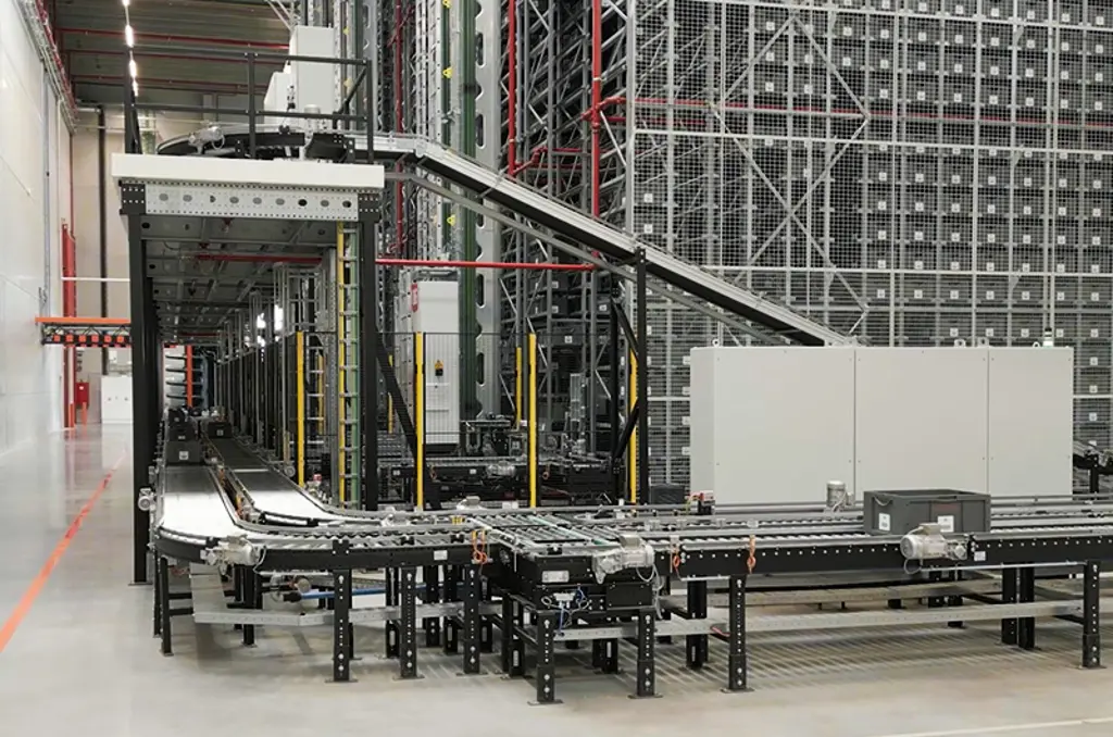Système automatisé de convoyeurs à rouleaux et à courroies dans un entrepôt, utilisé pour le transport de bacs et conteneurs, illustrant l’automatisation logistique et la manutention efficace.