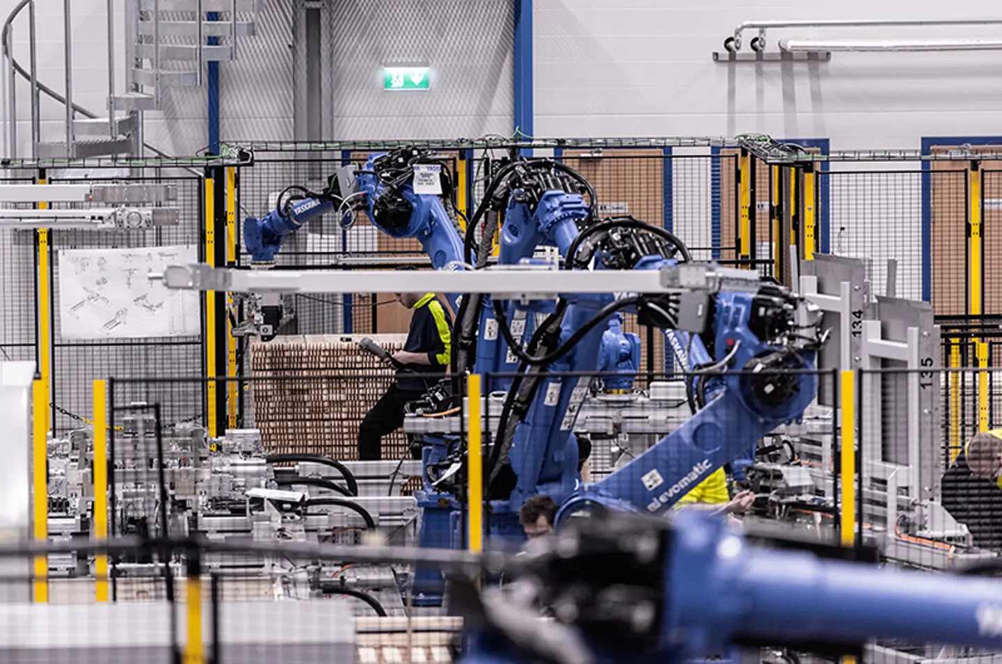 Bras robotiques industriels palettisant des marchandises à l’intérieur d’une cellule d’automatisation sécurisée.